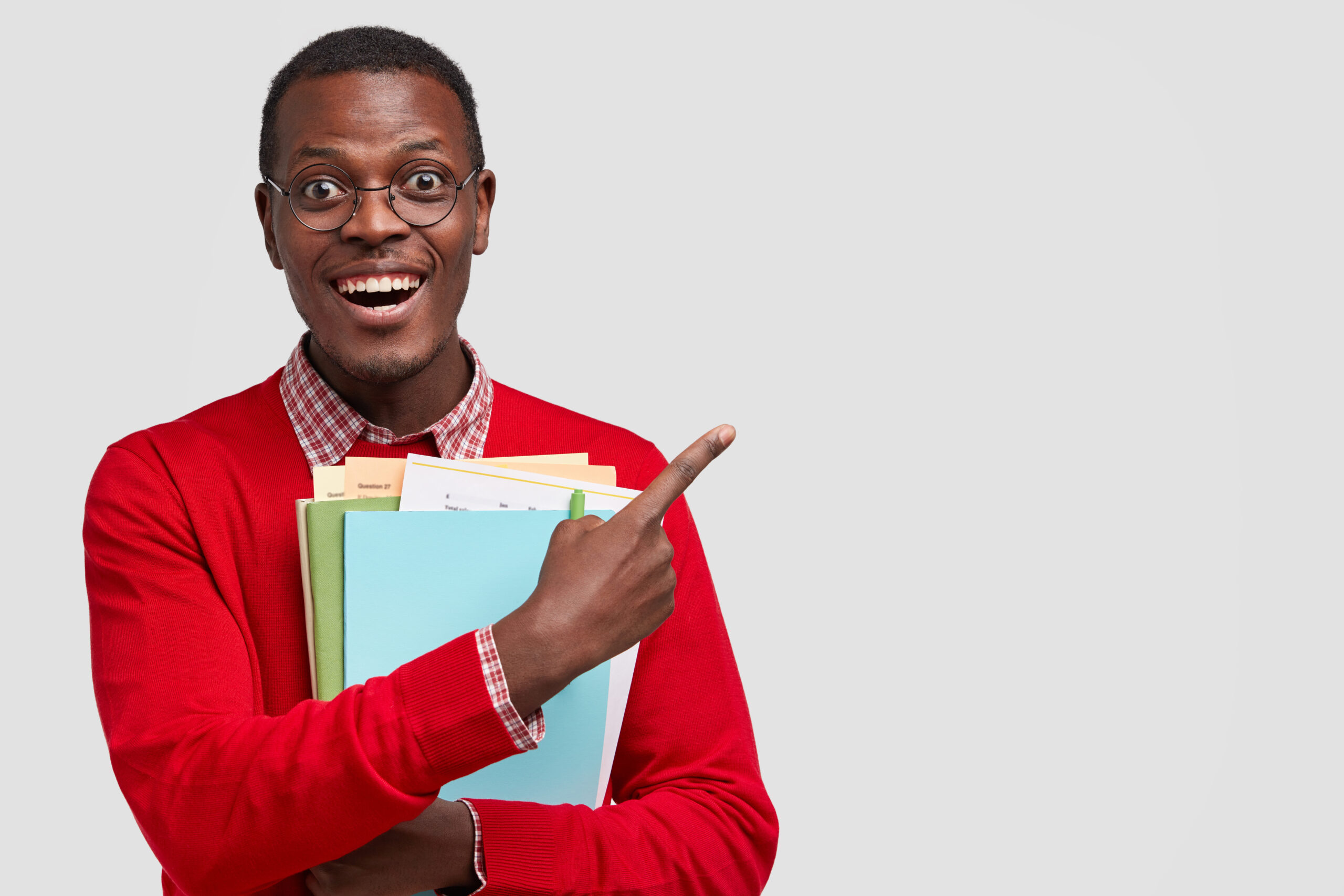 positive college student has dark skin carries folders book points with cheerful expression aside has toothy smile.jpg