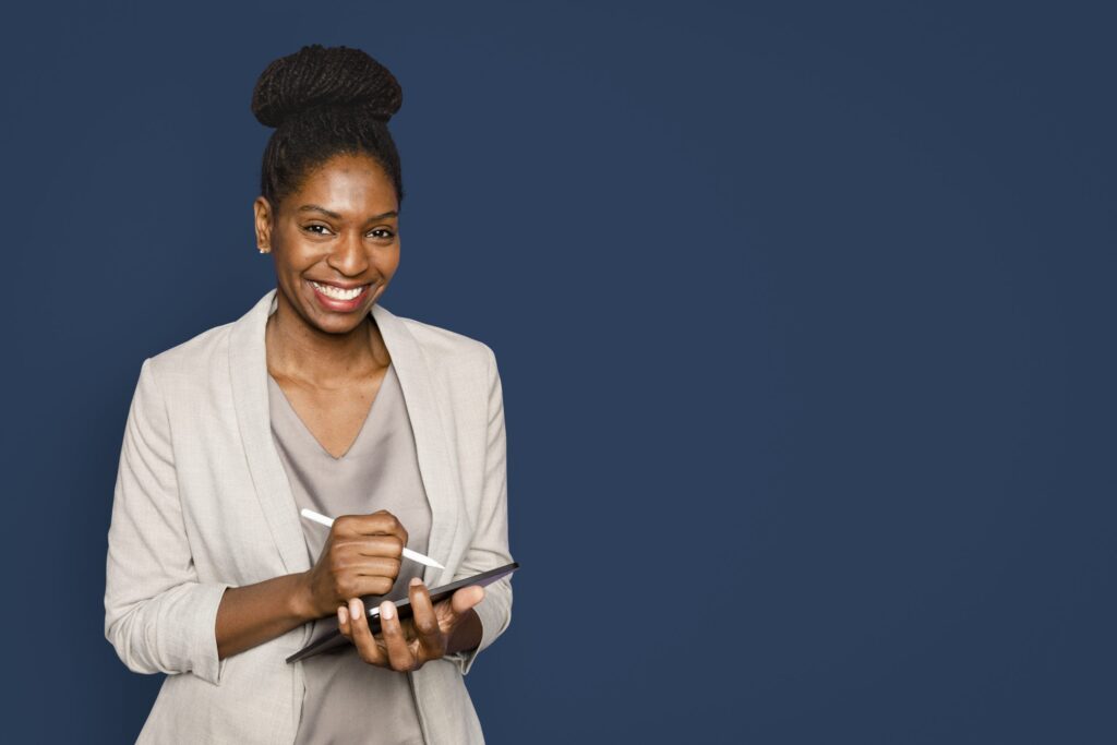 smiling woman writing notes tablet digital device 3 scaled.jpg